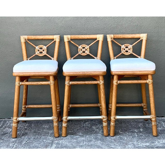 This exceptional set of three bar stools comes from the iconic McGuire Furniture Company of San Francisco, a brand...