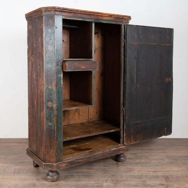 19th century Hungarian one-door armoire crafted in pine, retaining its original hand painted finish. The exterior features...