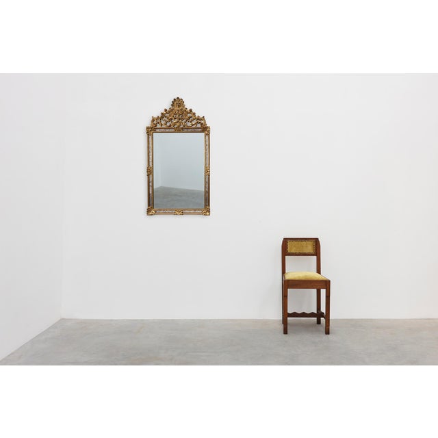 An ornate Rococo‑revival mirror by Deknudt, crafted in Belgium during the 20th century. The frame, molded in resin with a...