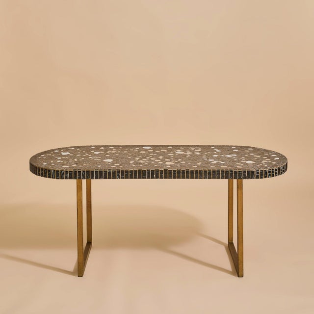 A French brass and ceramic mosaic coffee table from the 1960s, defined by its elongated oval form and richly textured...