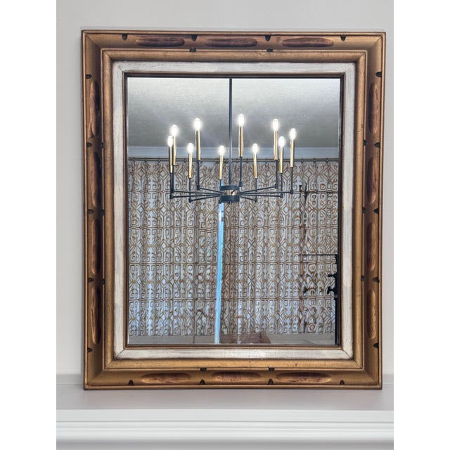 This mid century vintage wall mirror features a multi-layered frame combining a distressed, antiqued gold outer border...