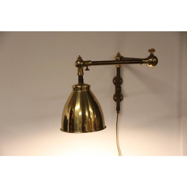 This wall lamp features a swivel arm, and is in iron and brass in a style reminiscent of Bauhaus. European Plug (up to...