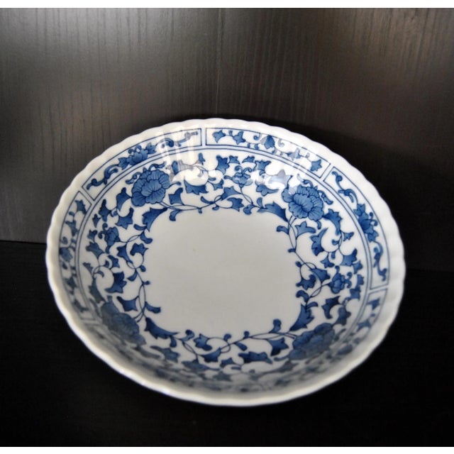 This shallow, scalloped edge Chinese Ming style porcelain dish is painted with a composite flower scroll band and lotus-...