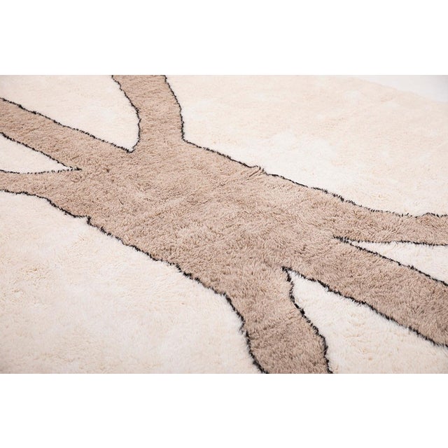 Artistic Moroccan hand-knotted wool rug in Soft Ivory with bold, abstract geometric shapes in Light Taupe, outlined in...