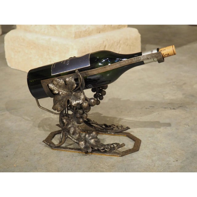 A charming wrought iron wine bottle cradle from France, circa 1900, this wine accessory features sprawling grapevines that...