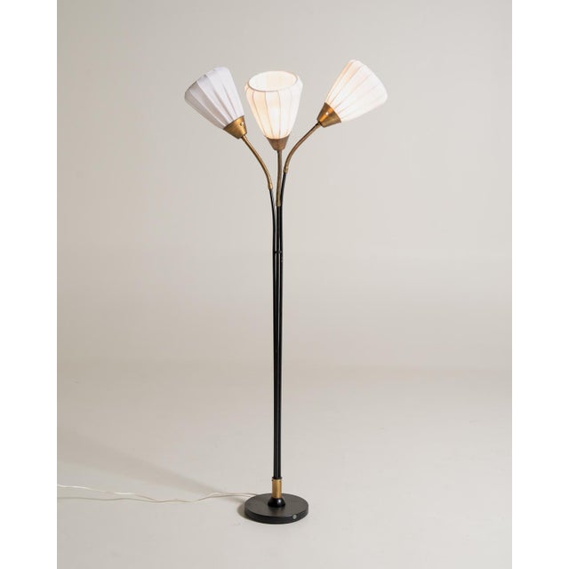 Black lacquered metal frame with brass details, three flexible arms, and white pleated fabric lampshades. Swedish...