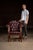 A stately mid-century leather club chair upholstered in deep burgundy tufted leather with brass nailhead trim and a solid...
