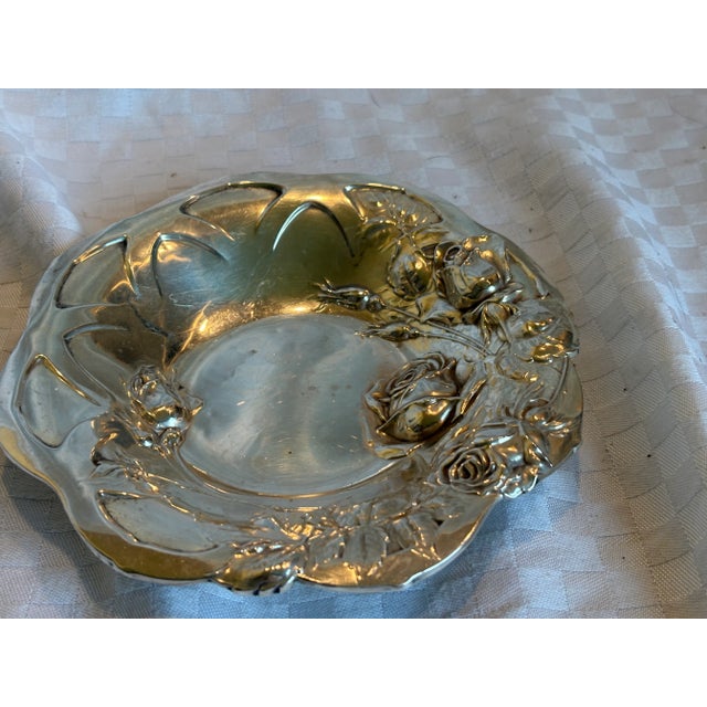 A sterling silver Art Nouveau dish with repousse roses overall. The piece is a shallow dish with a shaped edge. It is...