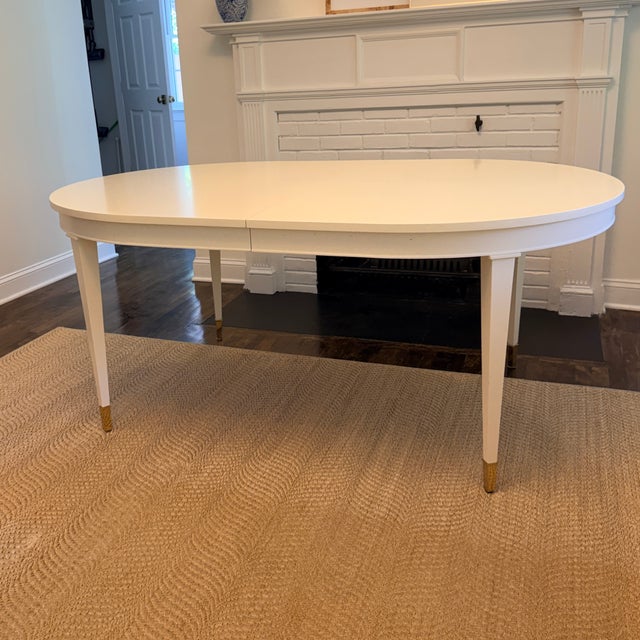 Highland House Hudson Dining Table A stunning oval dining table in a soft white finish with tapered legs and brass caps....
