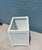 This is a white wicker trash can or wastebasket, likely vintage, featuring a rectangular shape and woven texture. This...