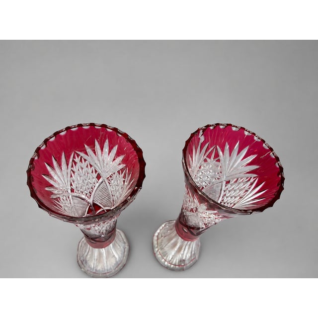 A beautiful pair of early 20th-century Bohemian cut crystal vases, handcrafted in clear lead crystal with deep ruby red...
