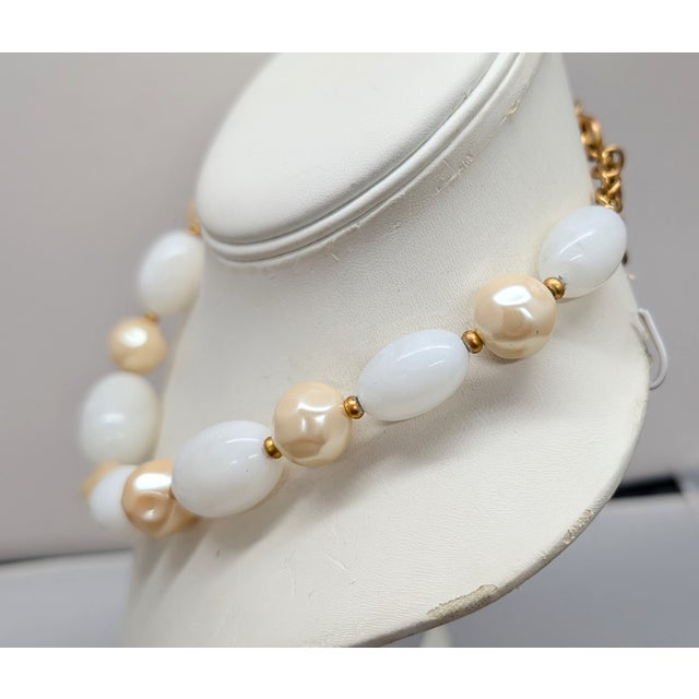 1980s goldtone ovoid white swirl beads with rounded off-white baroque pearl spacers necklace with lobster clasp. Marked...