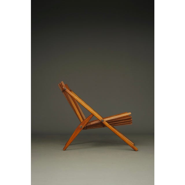 A unique sculptural lounge chair constructed from sections of beech wood connected using metal bars with bolts as...