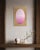 A pale lavender oval sits at the center of this canvas, its surface etched with a fine geometric grid that reads almost...