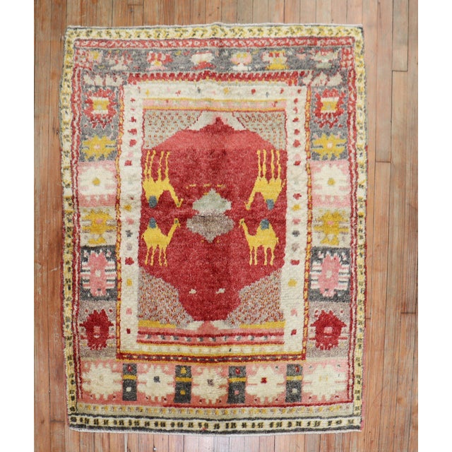 A scatter size village Turkish Rug with 4 gold camels on a bright red field hand-knotted in the middle of the 20th century...