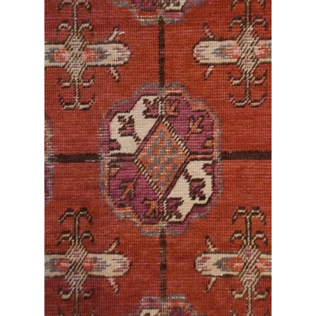 An early 20th Century Central Asian Samarkand rug with all-over floral medallion pattern on a burnt-orange background,...