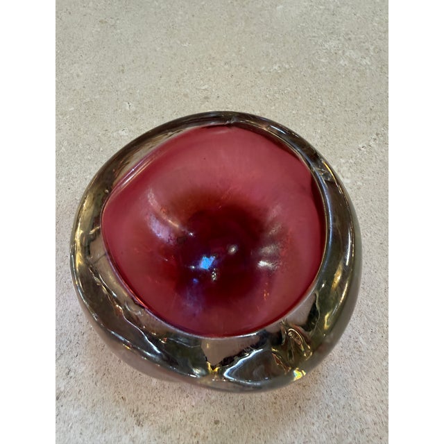 A sculptural Murano glass bowl crafted in the Sommerso technique, featuring a rich ruby red interior encased within a...