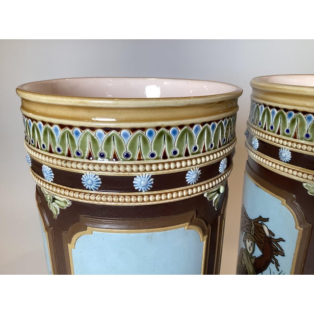 A pair of hand painted Royal Doulton Lambet footed cylinder vases, one depicting a maiden collecting tinder, the other a...