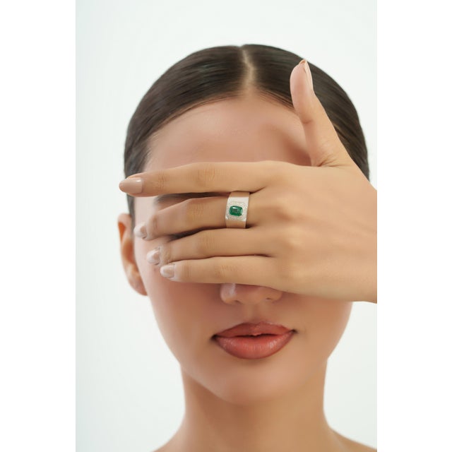 This Vintage Style Cushion Cut 1.2 Ct Emerald & Diamond Halo Signet Ring is crafted in 925 sterling silver and features a...