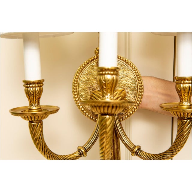 A pair of high quality and heavy gilt bronze Louis XVI Neoclassical Revival style three-arm wall sconces with rosette-...
