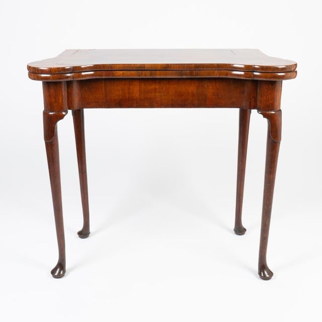 A rare, small-scale English Queen Anne flip-top concertina game table, circa 1720, crafted in walnut with book-matched,...