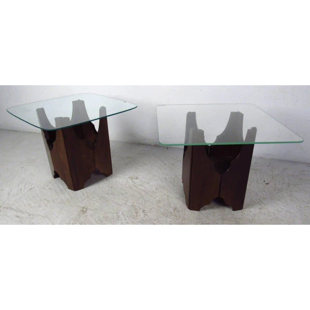 Vintage set of glass top end tables featuring beautifully sculpted bases with rich walnut grain throughout. Unique...