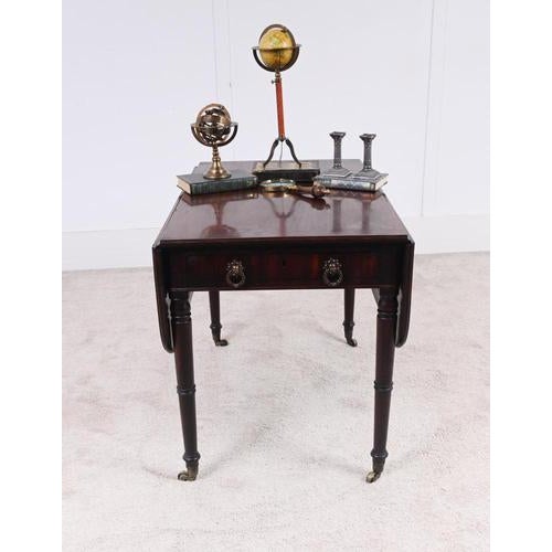 Elegant Georgian mahogany Pembroke table featuring twin drop leaves above a frieze drawer with original brass handles...