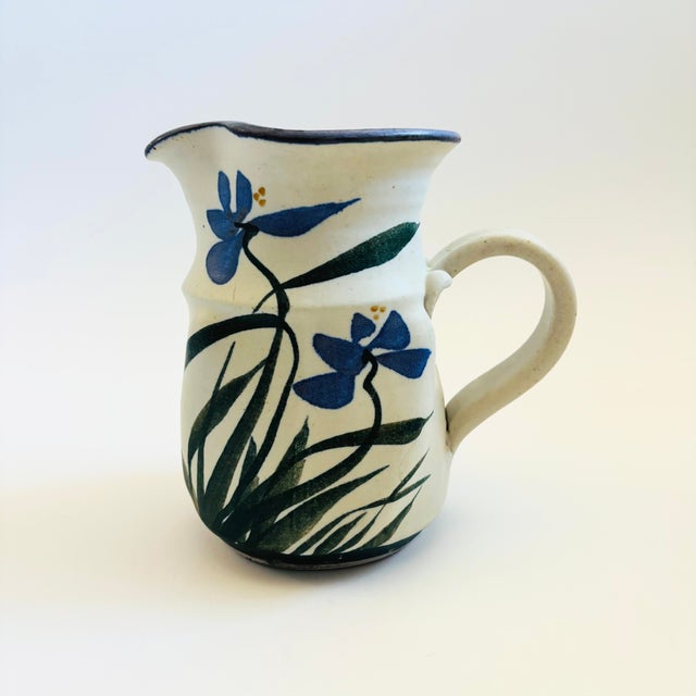 A vintage studio pottery pitcher. Pale gray base glaze with a lovely hand painted blue iris design with green leaves....