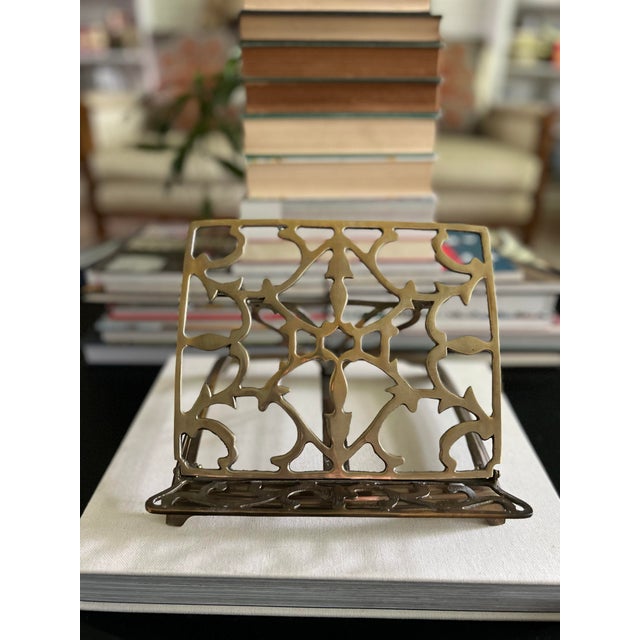 An ornate vintage folding book stand with an openwork brass-tone metal frame and adjustable easel-style support. The...
