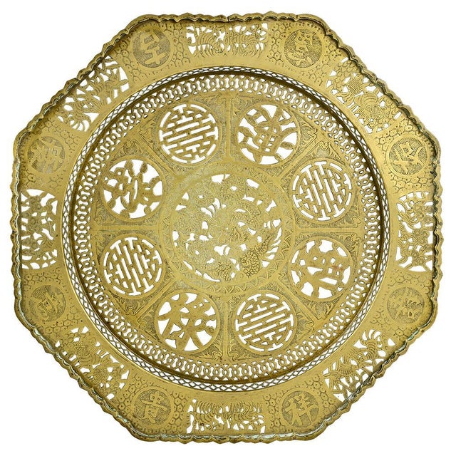 A Chinese table with a circular, openwork copper top, finely decorated with traditional motifs, resting on a carved wooden...