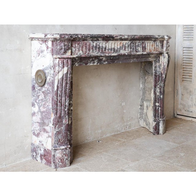 This large louis xvi fireplace features a convex fluted fronton adorned with rosettes at the corners. The fluted jambs...