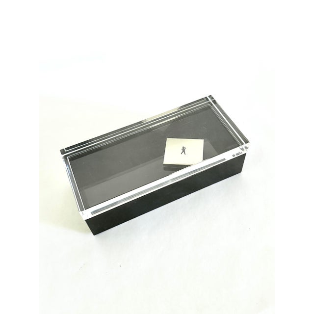A rectangular lucite lidded storage box designed by Alessandro Albrizzi. This long box has a polished black base and thick...