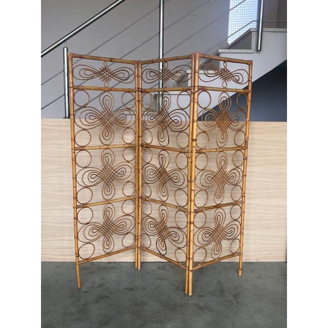 This Mid-Century-Modern eye-catching rattan or wicker and bamboo three-panel room divider with filigree decoration was...