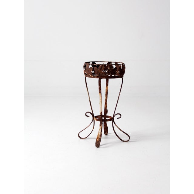 This beautifully aged vintage iron plant stand features a lipped top with a delicate foliage pattern. The slender base is...