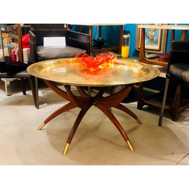 This is a truly stunning mid-century coffee table! It features a large hammered/detailed brass tray top depicting a...