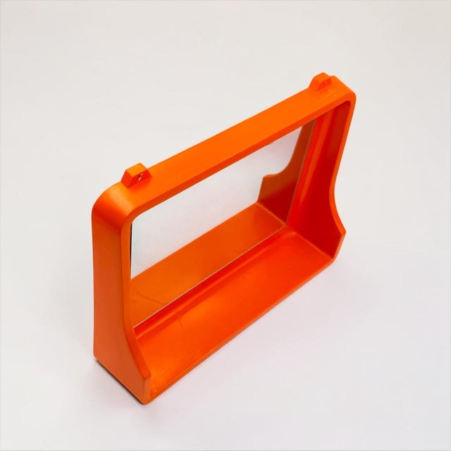 Sculptural wall mirror from the 1970s, made from vivid orange molded plastic and designed with an integrated lower shelf....