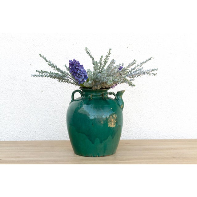 This antique pottery jar, bathed in a rich emerald green glaze, exudes a timeless charm and rustic elegance. Likely...