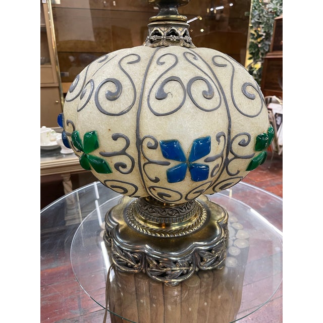 This sculptural fiberglass resin table lamp features a hand-decorated globular body with silver scrollwork, blue and green...