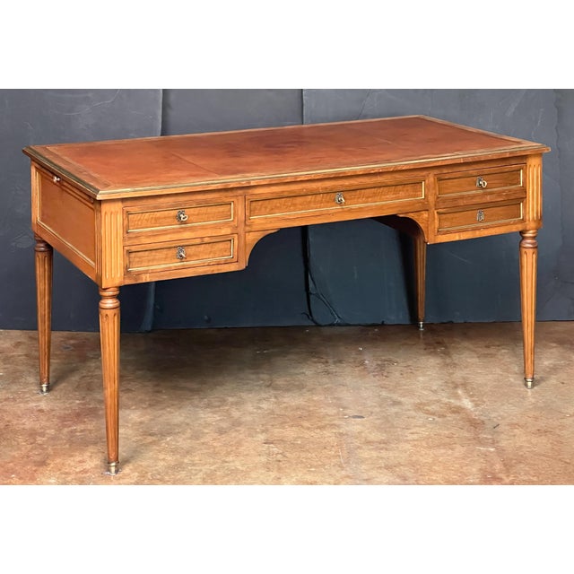 A handsome French writing table or desk in the Louis XVI style, featuring an embossed leather top set within an antique...