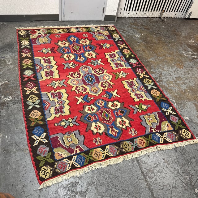 Design Plus Gallery presents a 7ft 2in × 10ft 4in Turkish Kilim Area Rug. This handwoven flatweave rug has a red field...