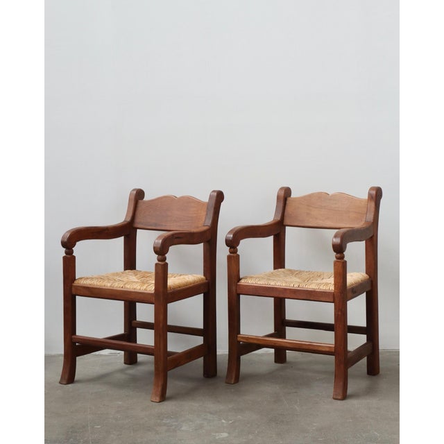 Pair of vintage Mexican walnut armchairs with curved arms and woven rush seats. Includes both chairs; the small table...