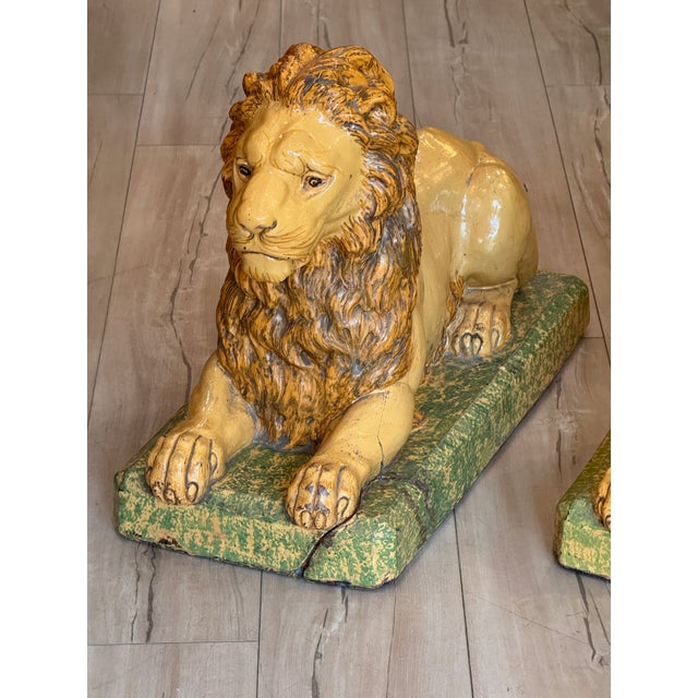 A fine pair of large faience lions, each modeled recumbent on a rectangular base glazed in mottled green. The lions are...