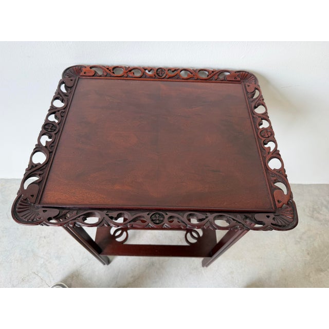 Elegant 1960’s vintage Chinese-style side table crafted from richly toned mahogany and featuring finely carved decorative...