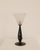 An openwork metal stem gives the lamp its slender architectural poise, with the glass shade completing the form in a...