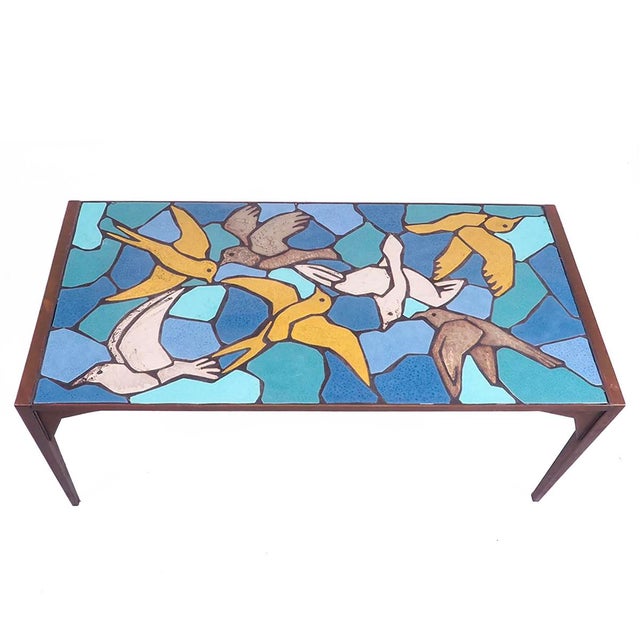 Stunning metal coffee table with a top of inlaid colorful tiles in the shape of birds, 1970s. The table has a heavy metal...