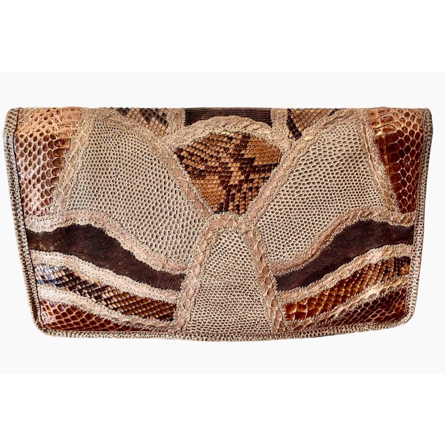 80s Carlos Falchi clutch in a tan leather base embellished with different patches of snakeskin in tones of tan and brown....