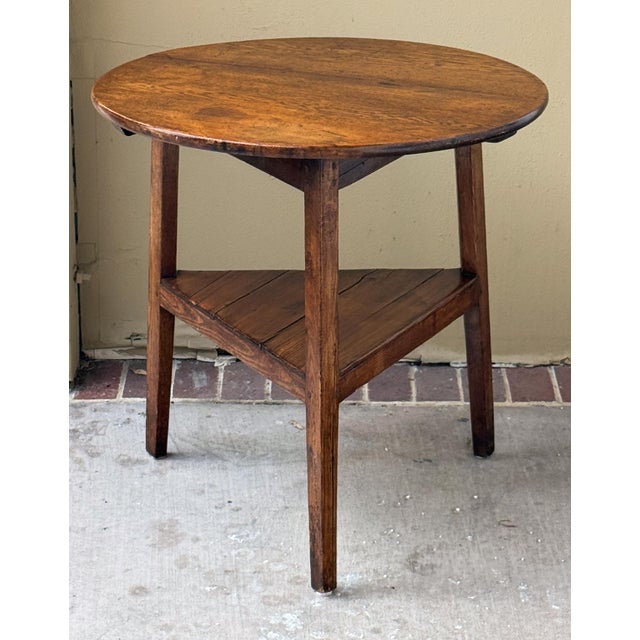 A handsome large English cricket table of patinated oak from the late Georgian Era, featuring the traditional round or...