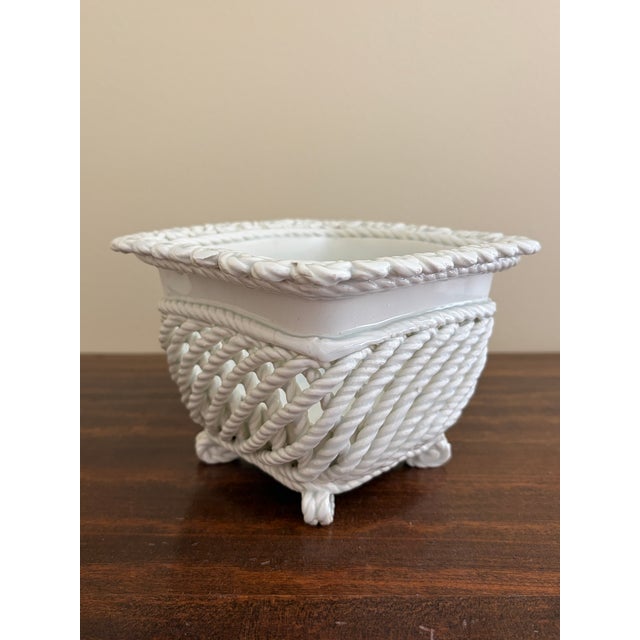 An elegant trompe l'oeil porcelain cachepot crafted in the form of a handwoven rope basket. Executed in glossy white...