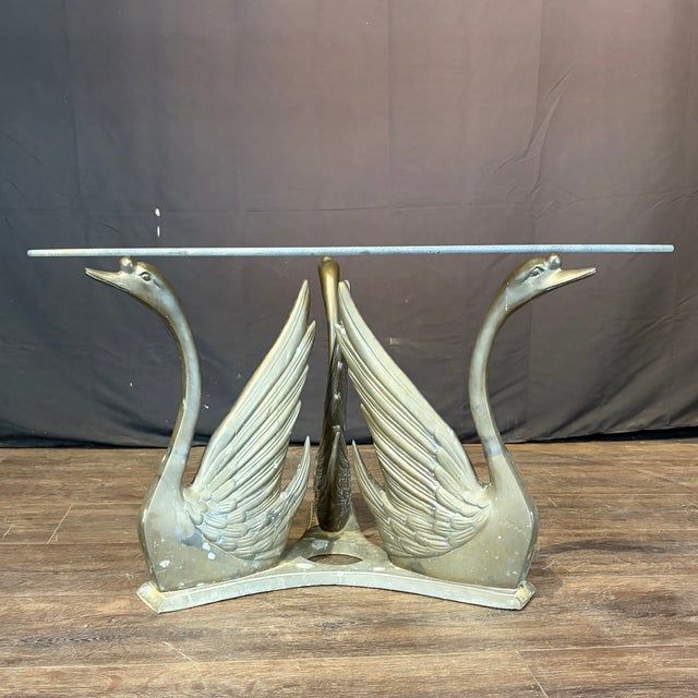 Elegant Hollywood Regency style vintage coffee cocktail table with round clear glass top, supported by a trio of graceful...