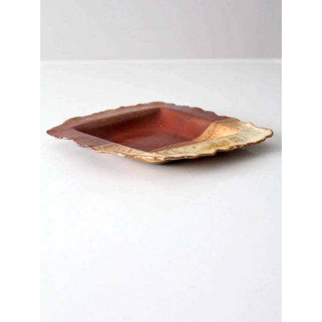 This vintage studio pottery plate features a hand-crafted shallow bowl form with a softly speckled glaze in earthy brown,...